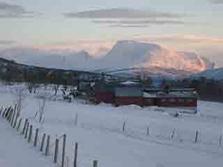 Snow-shaded farm and sunlit Mårfjell (Bakkeby, Norway)